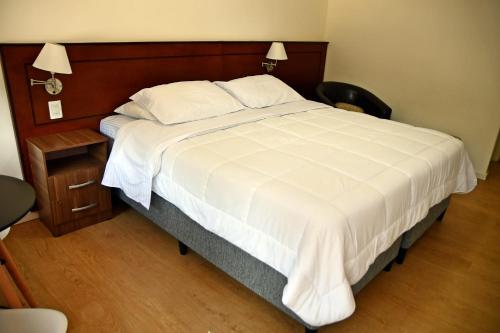 a bedroom with a large white bed with a wooden headboard at Trinidad Inn Trinidad in Trinidad