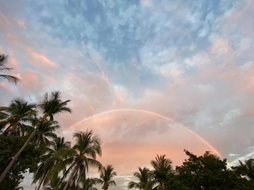 a rainbow in a cloudy sky with palm trees at Villa Poesía in Puerto Escondido