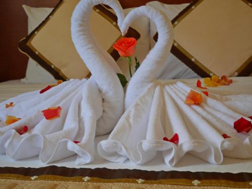 two swans dressed in white sitting on a bed at Hau Giang Hotel in Can Tho