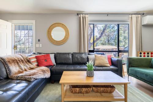 a living room with a black leather couch and a table at Scenic Mountain Getaway by the Park in Flagstaff