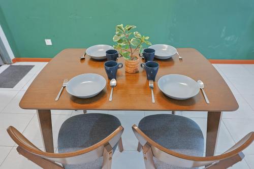 a wooden table with plates and utensils on it at Elegant Studio Escape at Emerald Avenue Cameron Clover Home 4-03 in Brinchang