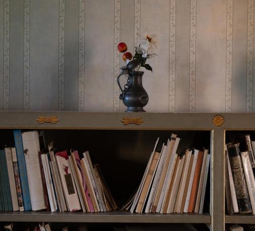 a book shelf filled with books and a vase with flowers at Il Casale Di Villa Rossi in Lucca