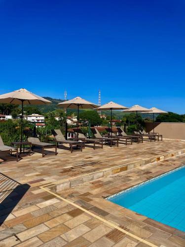 a group of chairs and umbrellas next to a pool at Villa do Éden in Lindóia