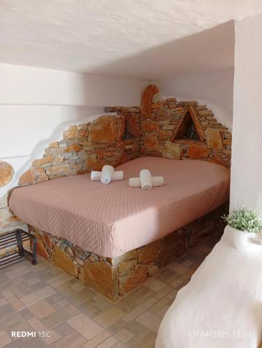 a bed in a room with a stone wall at Lucas B Panorama in Sikinos