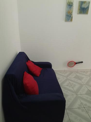 a blue couch with two red pillows in a room at Aconchego in Praia Grande