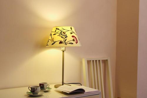Una lámpara sobre una mesa con un libro y tazas de café. en Casa Vista Serapo, en Gaeta