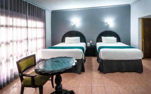 a hotel room with two beds and a glass table at InHouse Select Hacienda Tres Rios Hotel Culiacán in Culiacán