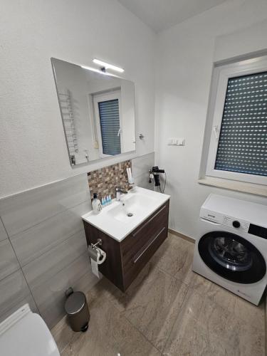 a bathroom with a sink and a washing machine at Villa BOTIĆ in Trogir