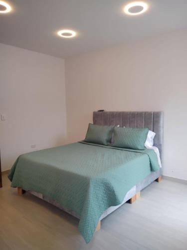a bedroom with a bed with a green comforter at Posada Chicara in El Cocuy