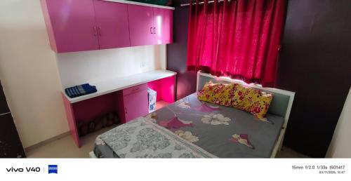 a small bedroom with pink cabinets and a bed at SM Home Stay in Pune
