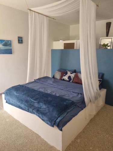 a bedroom with a bed with a blue and white canopy at Villa Nossa in Keur Goonde