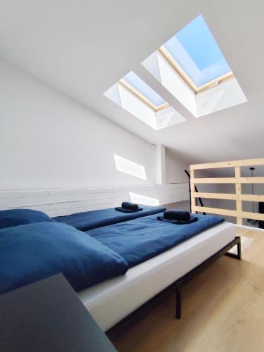 a bedroom with a bed with blue sheets and skylights at Fabryka Loft 3B # Nestapartamenty in Bielsko-Biała