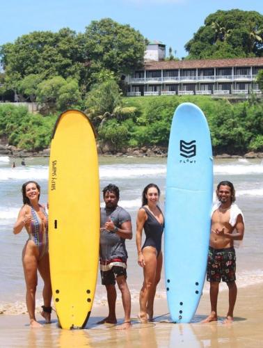 a group of people standing on the beach with surfboards at Barefoot Bungalow Hikka in Hikkaduwa
