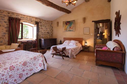 une chambre avec deux lits et un canapé et une fenêtre dans l'établissement Les fermes de Rieumal Hameau Cévenol Prestige, à Lasalle