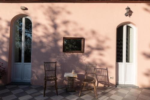a patio with three chairs and a table and a wall at Il Casale Di Villa Rossi in Lucca