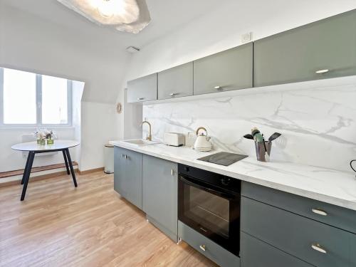 La cuisine est équipée de comptoirs blancs, d'un évier et d'une table. dans l'établissement Appartement centre ville Concarneau, à Concarneau