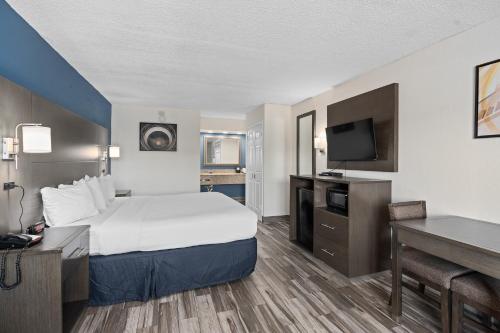a hotel room with a bed and a desk at Baymont by Wyndham Orlando East in Orlando