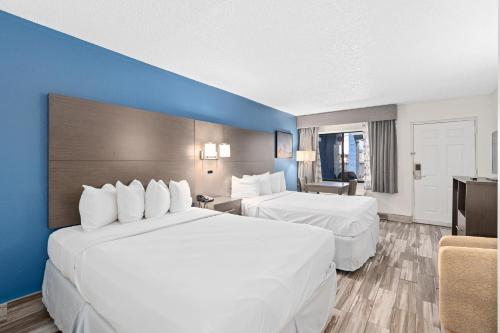 a hotel room with two beds and a blue wall at Baymont by Wyndham Orlando East in Orlando