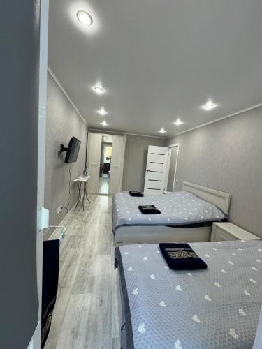 ein Schlafzimmer mit zwei Betten und einem Schreibtisch darin in der Unterkunft Уютные 1комнатные апартаменты на Казииту in Oral