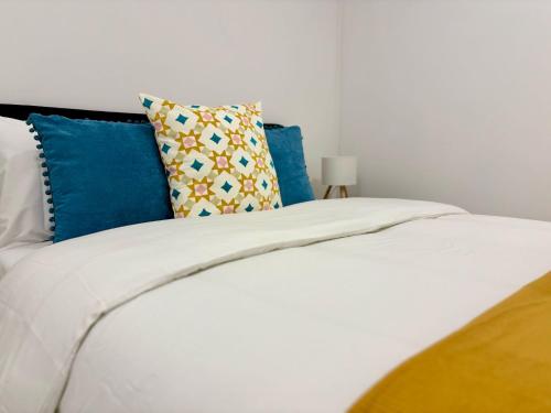 a white bed with blue pillows on top of it at Aurora Abode in Caldas da Rainha