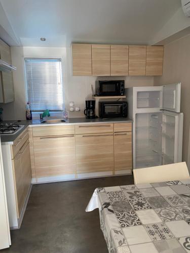 a small kitchen with wooden cabinets and a microwave at Mobile home 6personnes ,Alsace , munster France in Munster