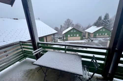 un banc assis sur un balcon dans la neige dans l'établissement Duplex in chalet Gérardmer view swimming pool, à Gérardmer