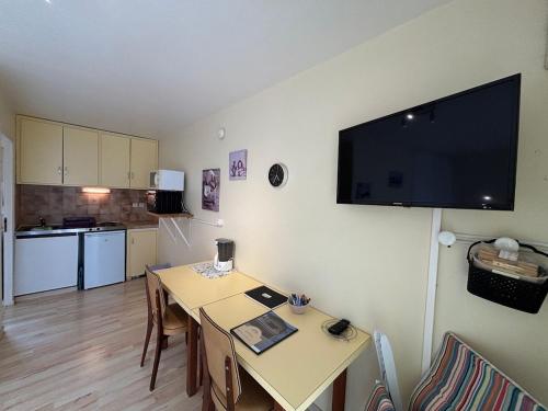 un salon avec une table et une télévision murale dans l'établissement StudiosMichel apt 14 terrasse thermes 400m à pied, à Cazaubon