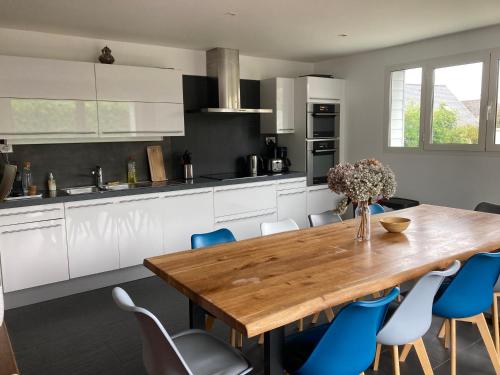 une cuisine avec une table en bois et des chaises bleues dans l'établissement Ty Boiss', à Sainte-Marine