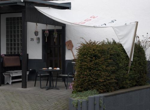 a patio with a table and a white awning at Ferienwohnung Körnernest in Ettringen