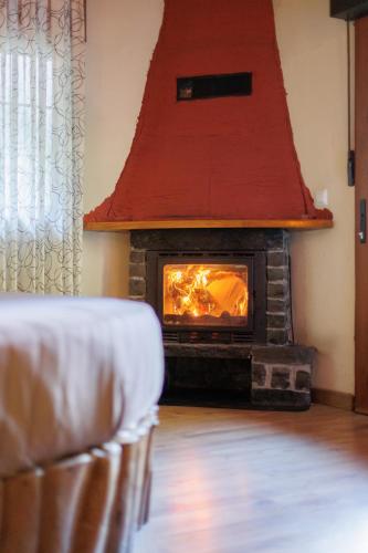 a fireplace with a red roof in a living room at Apartamento con jacuzzi a orillas del Río Sella in Canisquezo