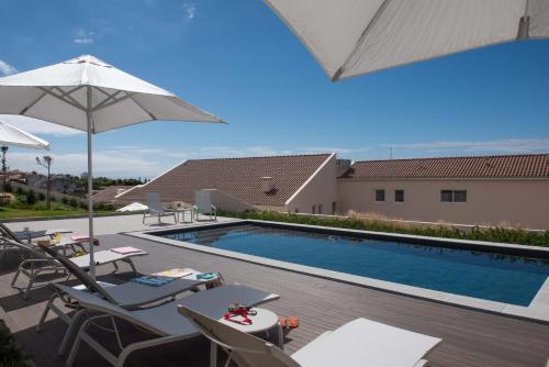 a swimming pool with patio furniture and an umbrella at Vila Marta - Garajau in Vila Franca do Campo