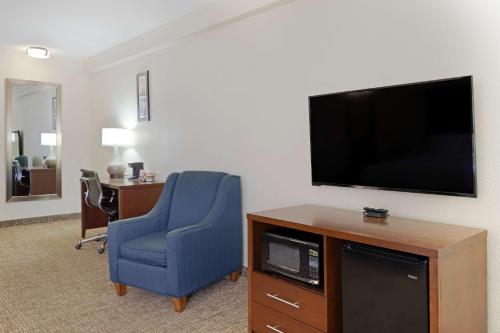 a hotel room with a tv and a blue chair at Comfort Inn & Suites Wichita Northeast in Wichita