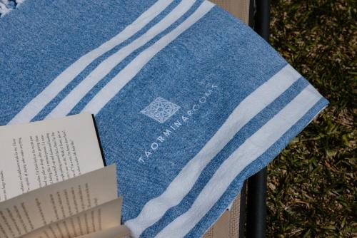 a blue towel with a book on a table at Villa Da Vinci Luxury Panoramic Apartments - Taormina rooms collection in Taormina