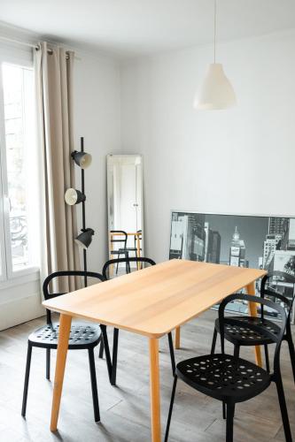 - une table en bois avec des chaises noires dans l'établissement T2 à 3mn du métro Mairie de Montrouge, à Montrouge