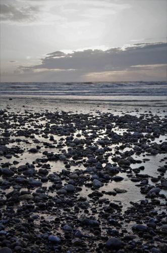 a beach filled with lots of rocks and the ocean at le galet Bleu in Criel-sur-Mer