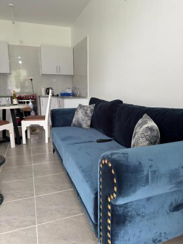 a blue couch in a living room with a kitchen at 1 bedroom beach apartment-Swan Homes in Malindi