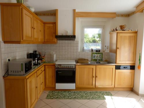 une cuisine avec des armoires en bois et un four à plaques de cuisson dans l'établissement Grand Gite, à La Celle-sous-Gouzon