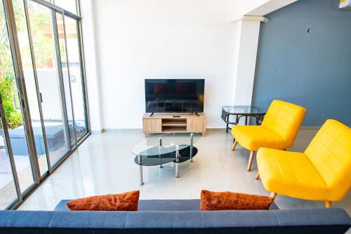 a living room with yellow chairs and a tv at Modern villa with private pool, 1 block from the Ocean in Chicxulub