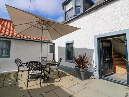 a patio with a table and chairs and an umbrella at 61 Seatown in Buckie