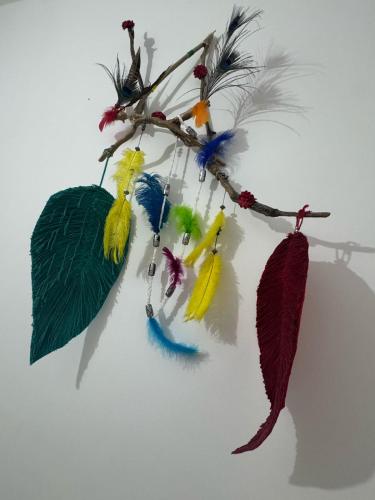 a branch with different colored feathers on it at Angel Mari a Doradal in Doradal