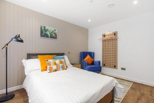 a bedroom with a bed and a blue chair at Chicstay Suites in High Wycombe