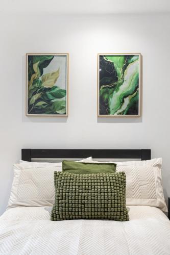 a bed with two paintings on the wall above it at Chicstay Suites in High Wycombe
