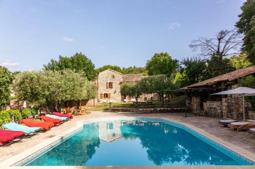 une piscine avec des chaises longues et une maison dans l'établissement Les fermes de Rieumal Hameau Cévenol Prestige, à Lasalle