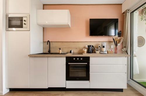 une cuisine avec des armoires blanches et un four noir dans l'établissement La perle du port, au Cap d'Agde