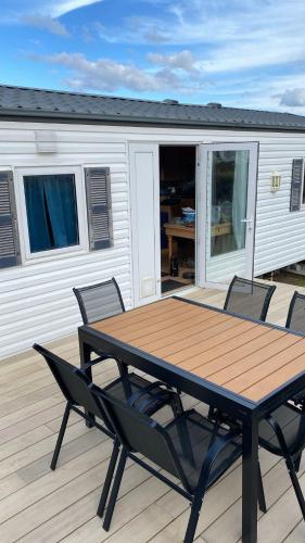 une table et des chaises en bois sur une terrasse dans l'établissement Mobil-Home le 70 du White Port, à Dinard