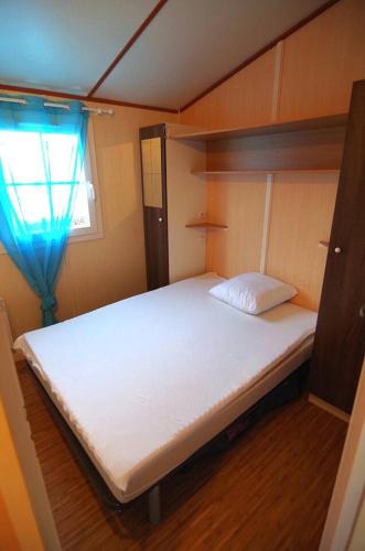 un grand lit blanc dans une chambre avec une fenêtre dans l'établissement Mobil-home a la campagne proche de la mer, à Criel-sur-Mer