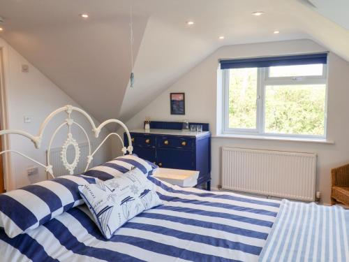 ein Schlafzimmer mit einem blau-weißen gestreiften Bett in der Unterkunft High Bullen Cottage in Morecombelake