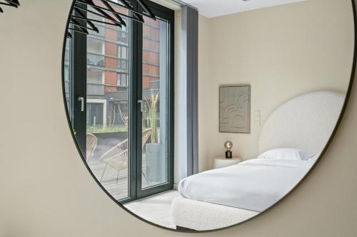 a mirror reflecting a bedroom with a bed and a window at Belval Spot Heart of Action in Esch-sur-Alzette