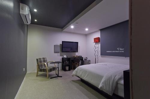 a bedroom with a bed and a desk and a tv at Hotel The May in Gwangju