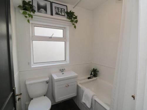a bathroom with a toilet and a window and a bath tub at Top-Notch Flat in Saltburn-by-the-Sea